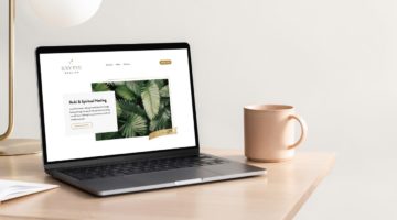 Laptop displaying a website with lush green leaf imagery, on a clean desk with a coffee mug.