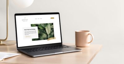 Laptop displaying a website with lush green leaf imagery, on a clean desk with a coffee mug.