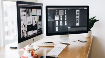 Dual computer monitors displaying website design and SEO tools setup.