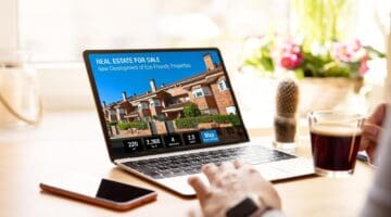 Laptop displaying real estate listings for sale with new development projects.